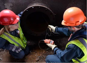 workers use a pumped gas monitor to sample air in a confined space